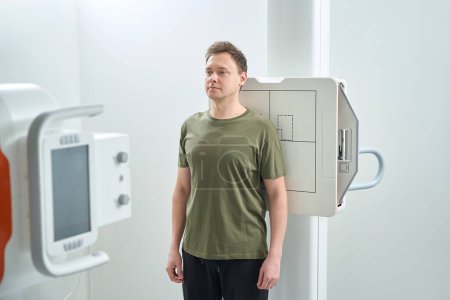 Foto de Paciente de pie en posición erguida mientras apoya su espalda contra el receptor de imagen frente a la unidad de rayos X - Imagen libre de derechos
