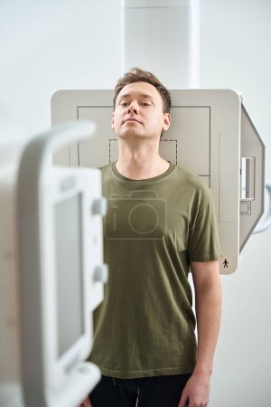 Téléchargez les photos : Patient en position verticale avec le menton relevé appuyé sur le dos contre le récepteur d'image devant la machine à rayons X - en image libre de droit