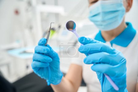 Photo for Dental hygienist checking sterility and cleansity of dental tools like mouth mirror with sophisticated magnification - Royalty Free Image