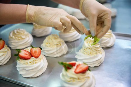 Photo for Close-up person garnishing a dessert with fresh strawberries and fluffy whipped cream to enhance the presentation and flavor of the baked goods - Royalty Free Image