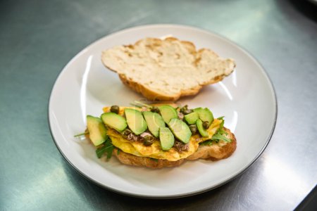 Photo for View to delicious just baked crois-sandwich with scrambled egg, arugula and avocado lying on the plate, tasty appetizer, culinary inspirations - Royalty Free Image