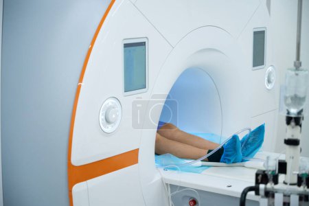 Téléchargez les photos : Photo recadrée d'une personne de sexe masculin allongée en position couchée sur une table de balayage à l'intérieur d'un portique IRM - en image libre de droit