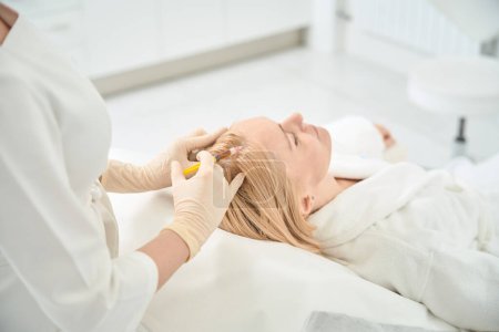 Photo for Qualified dermatocosmetologist making hair plasmolifting procedure to female client, suffering seborrhea and fragility of hair shafts, unique method that triggers body natural regeneration process - Royalty Free Image