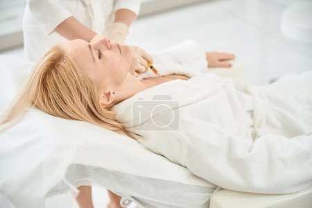 Qualified doctor cosmetologist making plasma injections into chest to female client, removing age-related skin changes and wrinkles, lifting and rejuvenating the skin, aesthetic medicine clinic