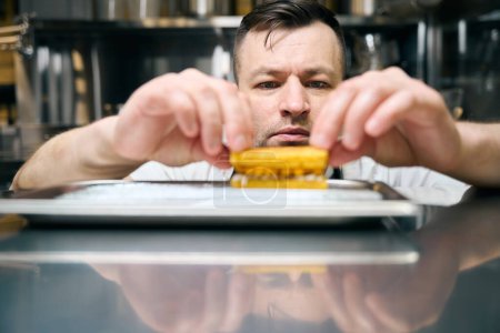 Enfócate en el fondo del chef masculino caucásico cocinando galletas borrosas en bandeja de hierro en la mesa del restaurante. Concepto de sabrosa alimentación saludable