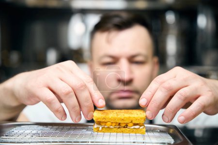 Photo for Focus on foreground of cookie cooking blurred caucasian male chef on iron tray in restaurant. Concept of delicious healthy eating - Royalty Free Image
