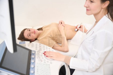 Foto de Cara oscura de ginecóloga caucásica haciendo ecografía de vientre embarazada de mujer joven europea en clínica. Concepto de embarazo y maternidad - Imagen libre de derechos