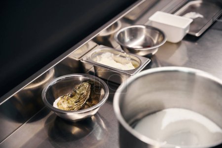 Foto de Mesa de planchar con utensilios de cocina, ostra y crema en cuencos en la cocina en el restaurante. Concepto de sabrosa alimentación saludable - Imagen libre de derechos