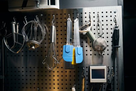Foto de Set de utensilios de cocina variados que cuelgan de la pared de la red de hierro en el restaurante moderno. Concepto de sabrosa alimentación saludable - Imagen libre de derechos