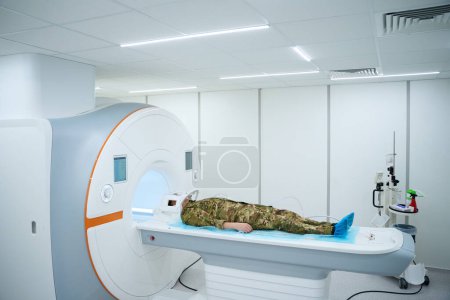 Servicekraft mit Plastikspule um den Kopf auf Magnetresonanztomographie-Tisch gelegt