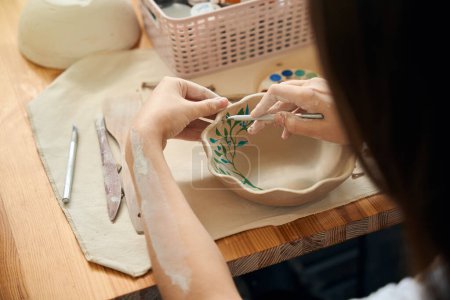 Femme méconnaissable peinture bol d'argile dans l'atelier de poterie