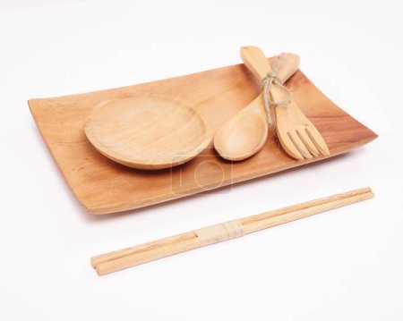 Téléchargez les photos : Cutlery made of wood crafts. An interesting combination of cutlery in the form of an aesthetic placemat, tray, cup, spoon, fork, chopsticks. Utilizing the remaining wood so that it can be useful. - en image libre de droit