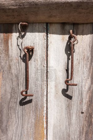 Old metal shutter hooks on wooden boards. Old wooden shutters. Wooden surface with old paint. Close-up 