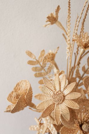 The bouquet flowers is made of straw on a white background. Straw weaving
