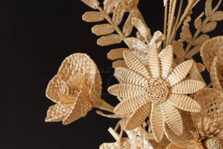 The bouquet flowers is made of straw on a dark background. Straw weaving