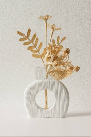 Eine Holzvase mit einem Blumenstrauß aus Stroh. Strohflechten