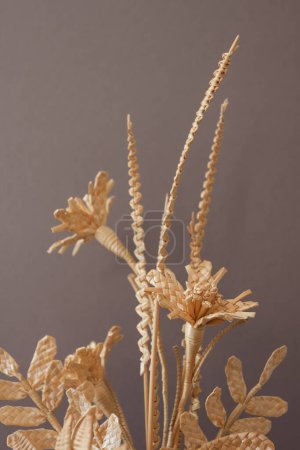 The bouquet flowers is made of straw on a gray background. Straw weaving