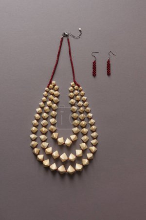 Straw necklace and beaded earrings on a gray background. Small depth of field. Straw weaving