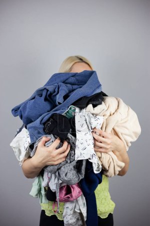 Photo for Woman holds a lot of crumpled clothes in her hands, white background, copy-paste - Royalty Free Image