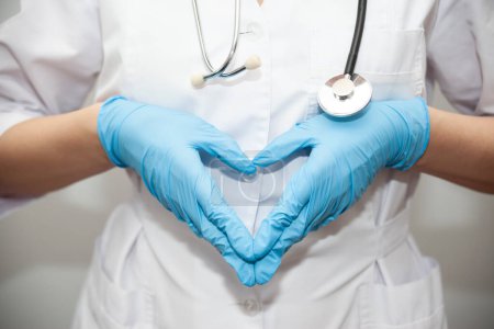 Photo for Woman with a medical mask and hands in latex glove shows the symbol of the heart. Doctor for the heart. Love to our pancreas. Love our medical professionals. - Royalty Free Image