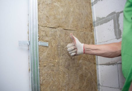 Photo for The worker insulates the walls with mineral wool for further cladding with plasterboard. Heat insulation and sound insulation of housing. - Royalty Free Image