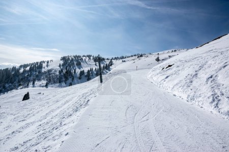 Photo for A groomed slope for skiers in the Austrian Alps with a cable car pole and fair weather. - Royalty Free Image