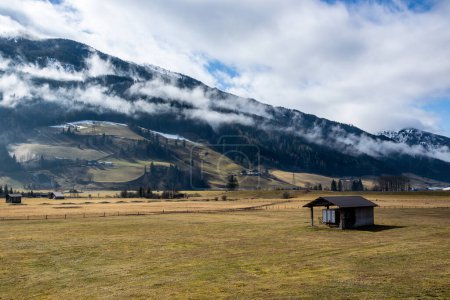 Photo for Clouds over the forest on the mountains in Austria. A grassy meadow in a valley with a wooden hut. - Royalty Free Image
