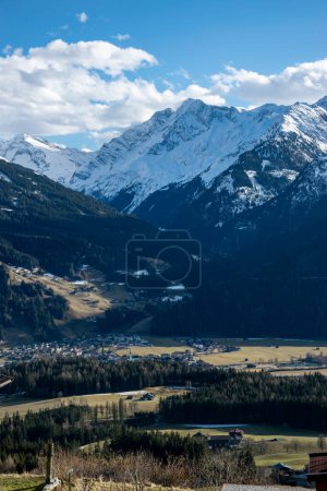 Photo for A valley in the Austrian Alps, snowy peaks of rocky mountains and a valley with meadows and a village. - Royalty Free Image
