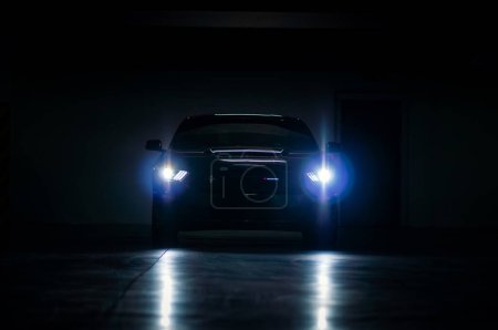 Foto de Brno, República Checa - 12 de septiembre de 2023: Ford Mustang negro con luces encendidas en un garaje oscuro. Coche deportivo en la oscuridad, vista frontal. - Imagen libre de derechos