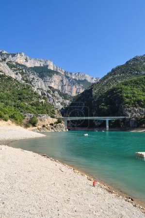 Téléchargez les photos : Le lac de Sainte-Croix bleu turquoise dans le sud de la France en Provence. Eau avec pédales, un pont pour les voitures et de hautes roches au-dessus du lac. - en image libre de droit
