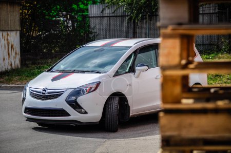Téléchargez les photos : Brno, République tchèque - 30 juin 2015 : La voiture familiale Opel Zafira se trouve dans la zone industrielle devant le hall d'assemblage. Voiture allemande blanche avec bande noire et rouge en feuille auto-adhésive. - en image libre de droit