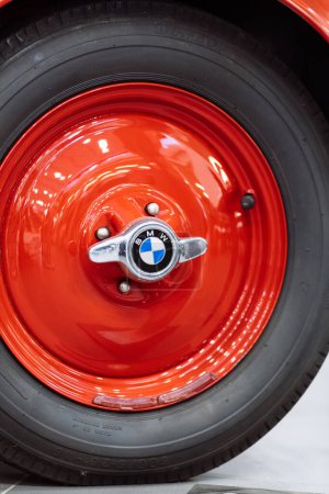 Téléchargez les photos : Brno, République tchèque - 25 novembre 2023 : Détail d'une roue rouge avec un pneu sur une vieille voiture historique. Boulon de serrage de roue avec logo BMW. - en image libre de droit