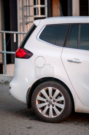 Téléchargez les photos : Brno, République tchèque - 20 mai 2023 : Voiture familiale blanche Opel Zafira Tourer MPV devant les entrepôts d'une zone industrielle. Détail roue arrière. - en image libre de droit