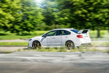 Téléchargez les photos : Brno, République tchèque - 16 mai 2024 : Voiture de sport Subaru WRX STI blanche. Subaru conduite rapide sur la route le long des arbres. - en image libre de droit