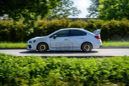 Téléchargez les photos : Brno, République tchèque - 16 mai 2024 : Voiture de sport Subaru WRX STI blanche. Subaru conduite rapide sur la route le long des arbres. - en image libre de droit