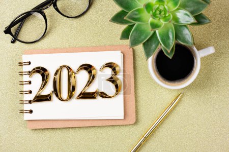 Téléchargez les photos : Nouvelles résolutions de l'année 2023 sur le bureau. Liste des résolutions 2023 avec cahier, tasse à café sur fond doré. Buts, résolutions, plan, action, concept de liste de contrôle. Nouvel An 2023 modèle, copie spac - en image libre de droit