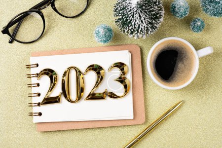 Photo for New year resolutions 2023 on desk. 2023 resolutions list with notebook, coffee cup, decorations on table. Goals, resolutions, plan, action concept. New Year 2023 template. Copy spac - Royalty Free Image