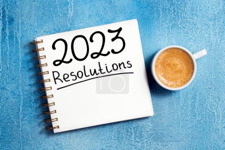 Téléchargez les photos : Nouvelles résolutions de l'année 2023 sur le bureau. Liste des résolutions 2023 avec cahier, tasse à café sur la table. Buts, résolutions, plan, action, concept de liste de contrôle. Nouvel An 2023 modèle, copie spac - en image libre de droit
