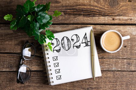 Nouvelles résolutions de l'année 2024 sur le bureau. 2024 liste des objectifs avec ordinateur portable, tasse à café, plante sur table en bois. Résolutions, plan, objectifs, action, liste de contrôle, concept d'idée. Nouvel An 2024 résolutions, espace de copie
