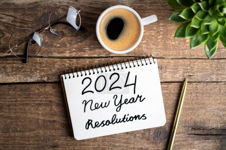 Nouvelles résolutions de l'année 2024 sur le bureau. 2024 liste des objectifs avec ordinateur portable, tasse à café, plante sur table en bois. Résolutions, plan, objectifs, action, liste de contrôle, concept d'idée. Résolutions du Nouvel An 2024. Espace de copie