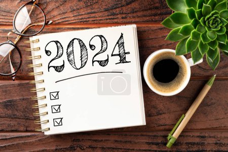 Neujahrsvorsätze 2024 auf dem Schreibtisch. 2024-Tore-Liste mit Notizbuch, Kaffeetasse, Pflanze auf Holztisch. Vorsätze, Pläne, Ziele, Maßnahmen, Checkliste, Ideenkonzept. Vorsätze für das neue Jahr 2024. Kopierraum