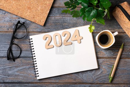 2024 Nouvelles résolutions de l'année sur le bureau. 2024 liste des objectifs avec ordinateur portable, tasse à café, plante sur table en bois. Résolutions, plan, objectifs, action, stratégie, succès, concept d'idée. Résolutions du Nouvel An 2024. Espace de copie