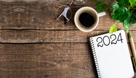 Neujahrsvorsätze 2024 auf dem Schreibtisch. 2024-Tore-Liste mit Notizbuch, Kaffeetasse, Pflanze auf Holztisch. Vorsätze, Pläne, Ziele, Maßnahmen, Checkliste, Ideenkonzept. Neujahrsvorsätze 2024
