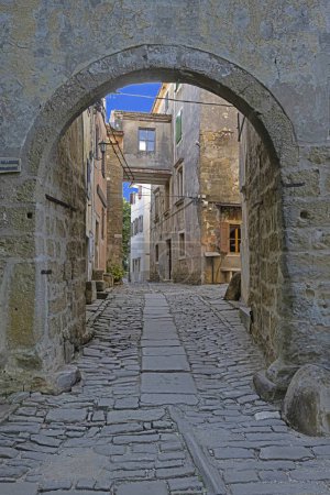 Foto de Vista a través de una puerta arqueada a lo largo de una calle empedrada en un antiguo pueblo sin gente durante el día - Imagen libre de derechos