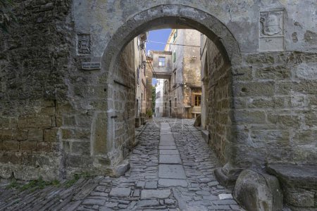 Foto de Vista a través de una puerta arqueada a lo largo de una calle empedrada en un antiguo pueblo sin gente durante el día - Imagen libre de derechos