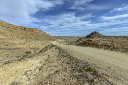 Foto de Imagen panorámica sobre un camino de grava a través del desierto como estepa en el sur de Namibia bajo un cielo azul en verano - Imagen libre de derechos