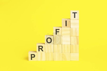 the word profit is written on a wooden cubes pyramide. blocks on a bright yellow background