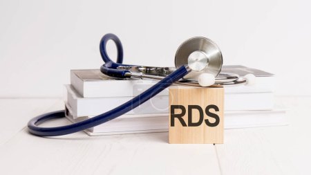 Text RDS steht auf einem Holzwürfel in der Nähe eines Stethoskops auf weißem Hintergrund