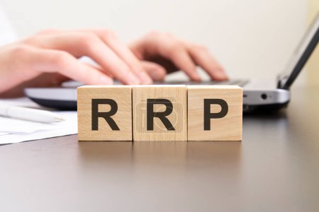 Photo for RRP - acronym from wooden blocks with letters. background hands on a laptop with blur - Royalty Free Image