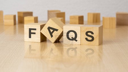 four wooden blocks with text FAQS on table. copy space. white background